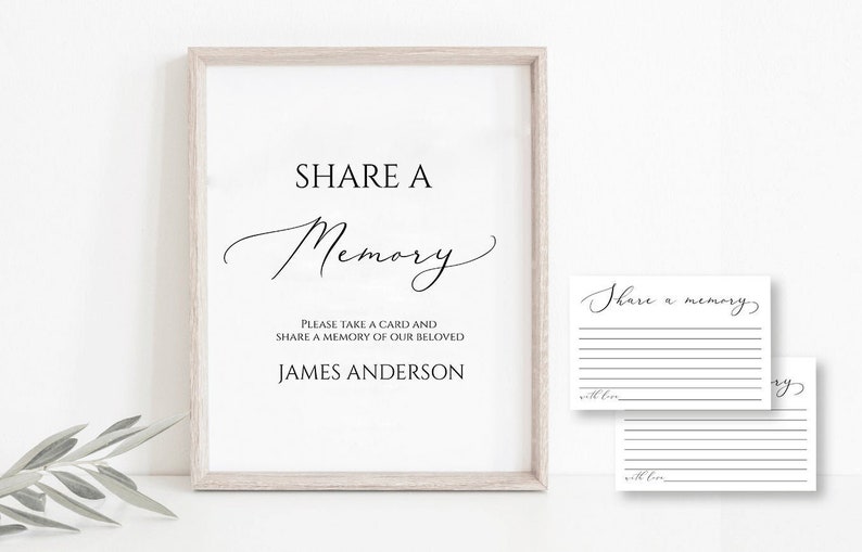 May include: A white framed sign with black text that reads "SHARE A Memory" and "Please take a card and share a memory of our beloved JAMES ANDERSON". Two blank white cards with black text that reads "Share a memory" are below the sign.