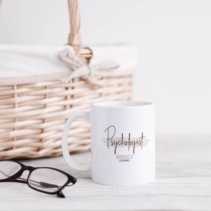 May include: White ceramic mug with a black and brown graphic that says "Psychologist Loading".