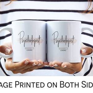 May include: Two white coffee mugs with black text that reads "Psychologist Loading" on each mug. The mugs are held by a person wearing a black and white striped sweater.