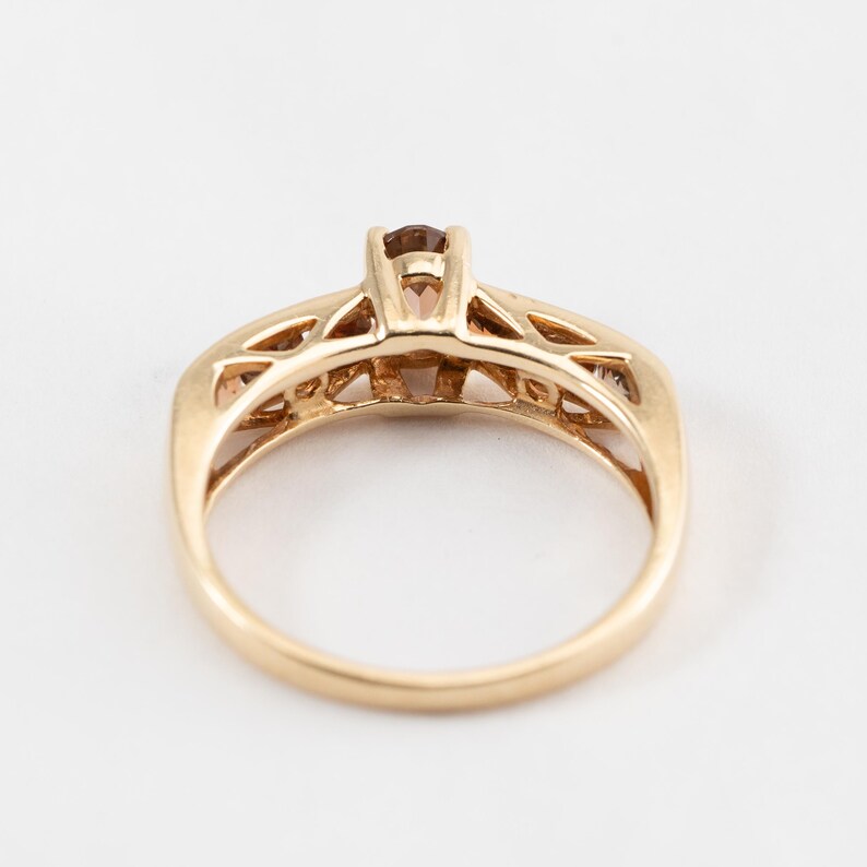 Puede incluir: Un anillo de oro con una piedra preciosa marr&oacute;n en el centro y piedras preciosas m&aacute;s peque&ntilde;as en la banda.
