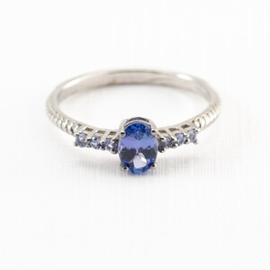 May include: A silver ring with a large oval blue gemstone and smaller blue gemstones on the band.