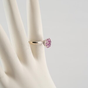 May include: A silver ring with a cluster of pink gemstones set in a flower shape.