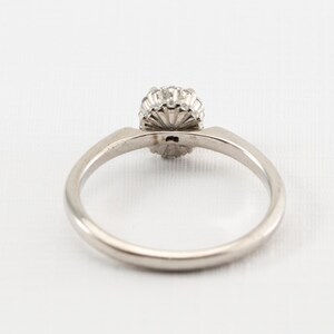 May include: A silver ring with a round, clear stone surrounded by smaller stones.