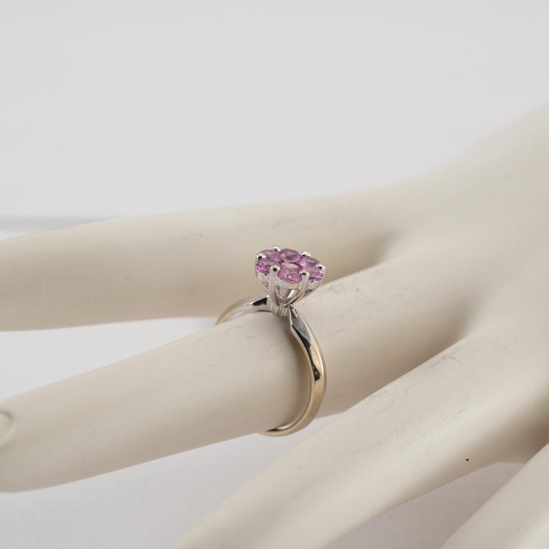 May include: A silver ring with a cluster of pink gemstones set in the center.