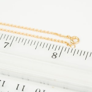 May include: A gold chain necklace measuring 8 inches long, laid out on a ruler.
