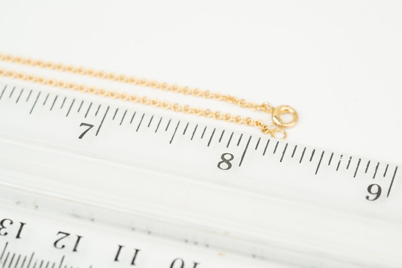 May include: A gold chain necklace measuring 8 inches long, laid out on a ruler.