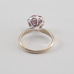 May include: A gold ring with a cluster of pink sapphires set in a white metal setting.
