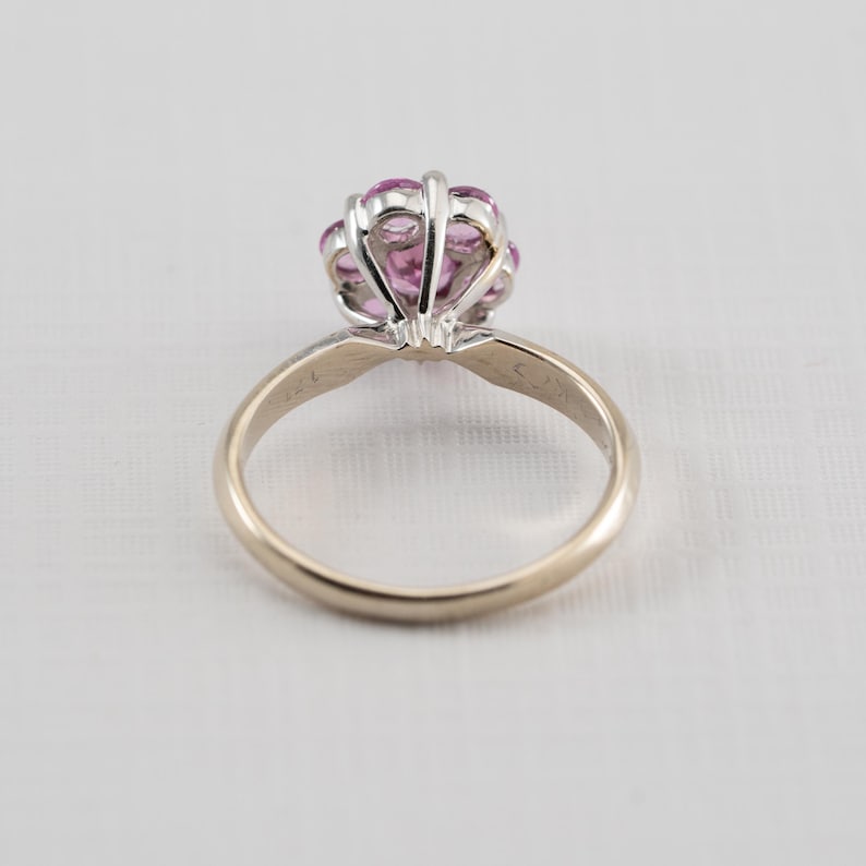 May include: A gold ring with a cluster of pink sapphires set in a white metal setting.