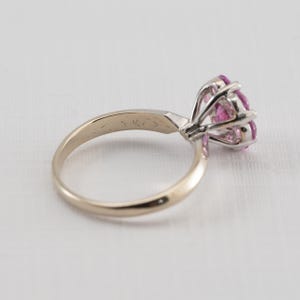 May include: A gold ring with a pink gemstone set in a prong setting. The ring is marked "14K" on the inside of the band.