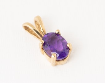 May include: A gold pendant with a purple oval amethyst gemstone.