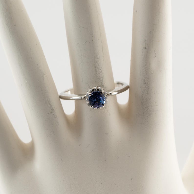 May include: A silver ring with a blue gemstone set in a crown-shaped halo.