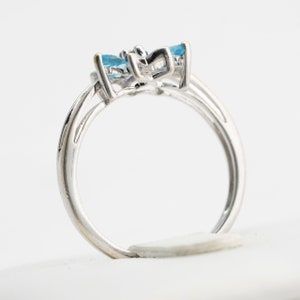 Pu&ograve; includere: Un anello d'argento con tre pietre preziose blu incastonate in una fascia delicata e attorcigliata.