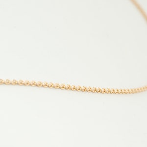 May include: A delicate gold chain necklace with a fine, round link design.