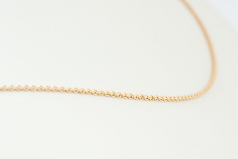 May include: A delicate gold chain necklace with a fine, round link design.