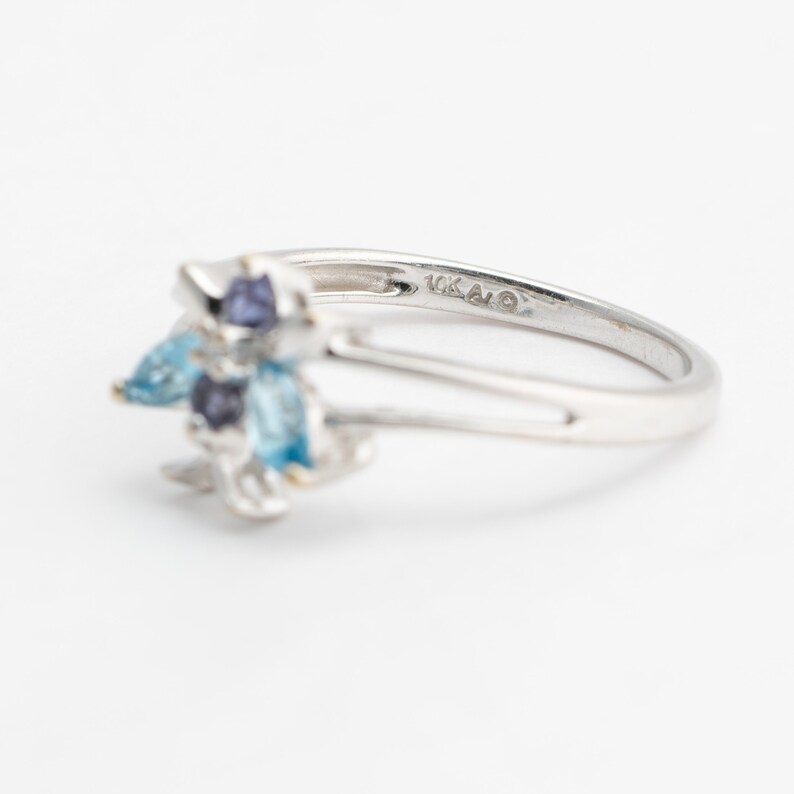 Pu&ograve; includere: Un anello d'argento con un gruppo di pietre preziose blu e viola. L'anello &egrave; contrassegnato "10K AO" sulla fascia interna.