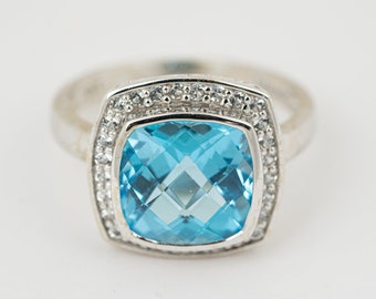 May include: A silver ring with a large, square-shaped blue topaz gemstone surrounded by a halo of smaller diamonds.