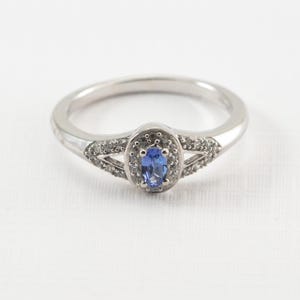 May include: A silver ring with a blue oval gemstone surrounded by smaller white gemstones.