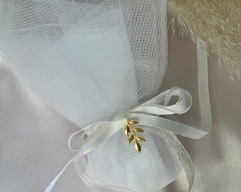 May include: A white tulle bag tied with a white satin ribbon and a gold leaf charm.