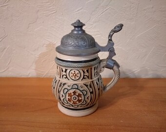 Vintage German ceramic beer mug with an elegant metal lid.