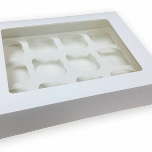 Op de afbeelding: Witte kartonnen cupcake doos met een transparant venster, ontworpen om 12 cupcakes te bevatten.