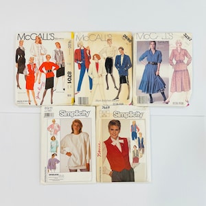 May include: A collection of vintage sewing patterns for women's clothing. The patterns are from McCall's and Simplicity brands. The patterns include designs for shirts, blouses, skirts, dresses, and sweaters. The patterns are in various colors, including red, blue, green, and white.