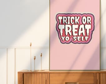 以下が含まれることがあります： レトロなフォントで「TRICK OR TREAT YO' SELF」というテキストが入った、額入りのピンク色のポスター。ポスターは木製のキャビネットに飾られています。左上隅には「sassie prints」のロゴがあります。