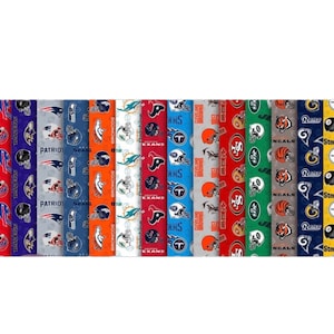 May include: A collection of fabric rolls featuring various NFL team logos and colors. The fabrics display team names and helmet designs, including the Raiders, Bills, Patriots, Broncos, and Steelers. The rolls are arranged side by side, showcasing a variety of team-themed patterns.