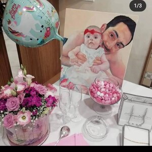 Può includere: Un dipinto di un padre e una figlia, con il padre che tiene la figlia tra le braccia. Il dipinto è su tela ed è incorniciato. Davanti al dipinto c'è una ciotola di caramelle rosa e bianche piena di caramelle rosa e bianche. Nell'angolo in basso a sinistra dell'immagine c'è un mazzo di fiori rosa in un cestino rosa e bianco. Nell'angolo in basso a destra dell'immagine c'è una borsa regalo bianca con un nastro argentato e un'etichetta argentata che dice "Amitie Jewelry".