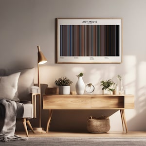 May include: A minimalist living room with a light grey sofa, a wooden side table, a lamp, and a framed print of a movie poster with a bar code design. The poster reads "ANY MOVIE ANY YEAR".