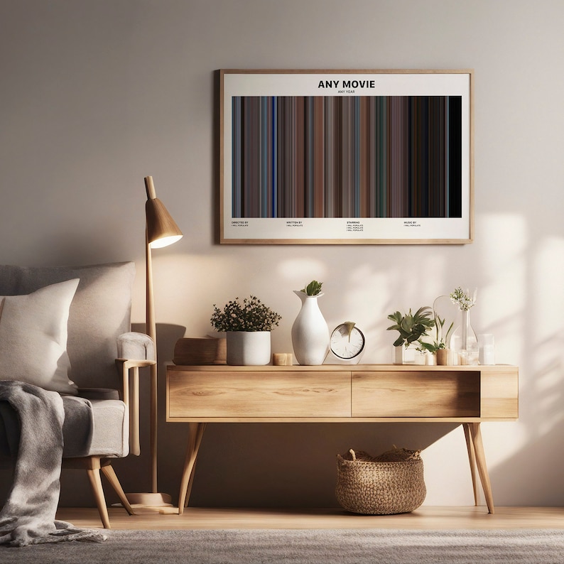 May include: A minimalist living room with a light grey sofa, a wooden side table, a lamp, and a framed print of a movie poster with a bar code design. The poster reads "ANY MOVIE ANY YEAR".