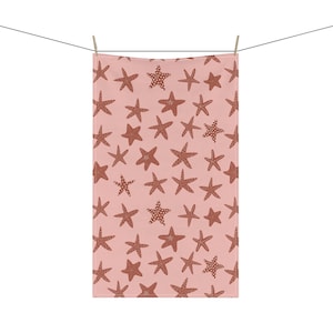 May include: A pink kitchen towel with a repeating pattern of brown starfish.