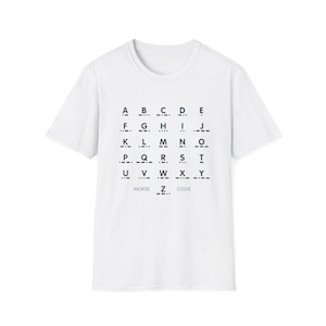 Può includere: T-shirt bianca con un grafico dell'alfabeto Morse nero stampato sul davanti. Il grafico include le lettere dalla A alla Z, con le parole "Morse Code" sotto. La maglietta ha maniche corte e girocollo.