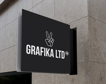 May include: A black rectangular sign with the text "GRAFIKA LTD" in white, along with a white hand symbol making a peace sign. The sign is mounted on a light-colored stone wall.