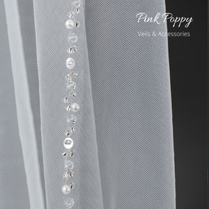 Beautiful veil in the softest ivory tulle. Edged with an abundance of sparkle and pearls, this pretty veil will compliment all styles of wedding dresses without upstaging the Bride to be. Lowest prices and great quality