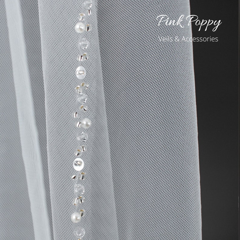 Beautiful veil in the softest ivory tulle. Edged with an abundance of sparkle and pearls, this pretty veil will compliment all styles of wedding dresses without upstaging the Bride to be. Lowest prices and great quality