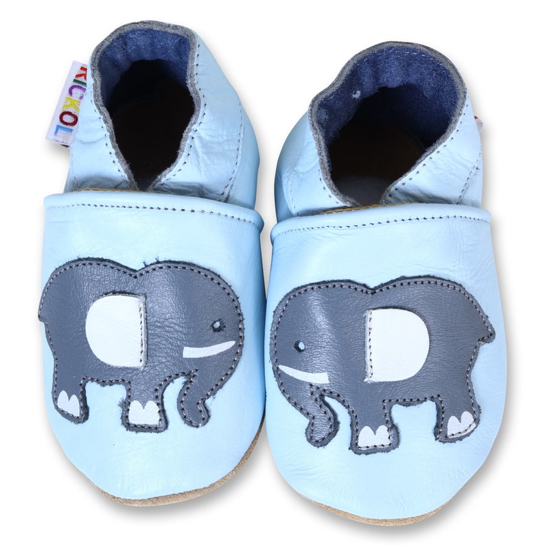 Puede incluir: Un par de zapatos de beb&eacute; de color azul claro con un dise&ntilde;o de elefante. Los zapatos est&aacute;n hechos de cuero suave y tienen un ajuste c&oacute;modo.