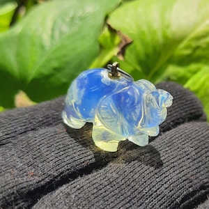 May include: A blue and white opal elephant charm pendant with a silver loop for attaching to a necklace or bracelet.