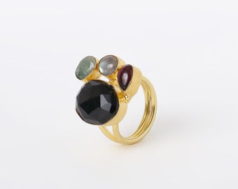 May include: Gold ring with a black gemstone and three smaller gemstones in green, grey, and red.