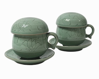 May include: Two green ceramic teacups with lids and matching saucers. The cups and saucers have a floral design.