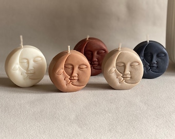 May include: Five round candles with a moon and face design. The candles are in various colors including white, beige, brown, and black.