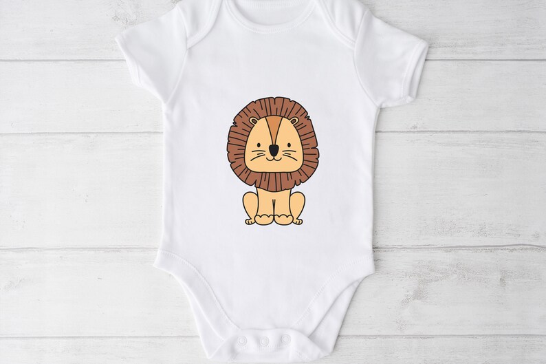 May include: White baby onesie with a cartoon lion wearing a brown mane. The lion is sitting down with its paws in front of it.