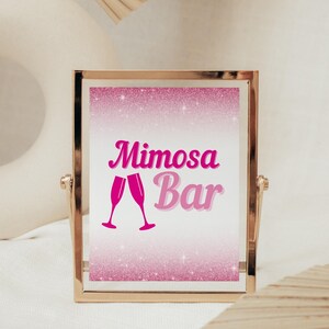May include: A gold-framed sign with a pink glitter background and the text "Mimosa Bar" in pink cursive lettering. Two pink champagne glasses are depicted below the text.
