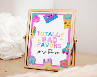 Op de afbeelding: Een roze en wit bord met de tekst "Totally Rad Favors Please Take One" in regenboogkleuren. Het bord is versierd met afbeeldingen in de stijl van de jaren 80, zoals een cassettebandje, een trollpop, een gameconsole, rol schaatsen en een Rubik's Cube.