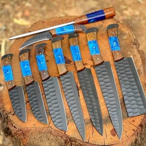 May include: A set of nine kitchen knives with black blades and wooden handles with blue resin inlays. The knives are arranged on a wooden surface.