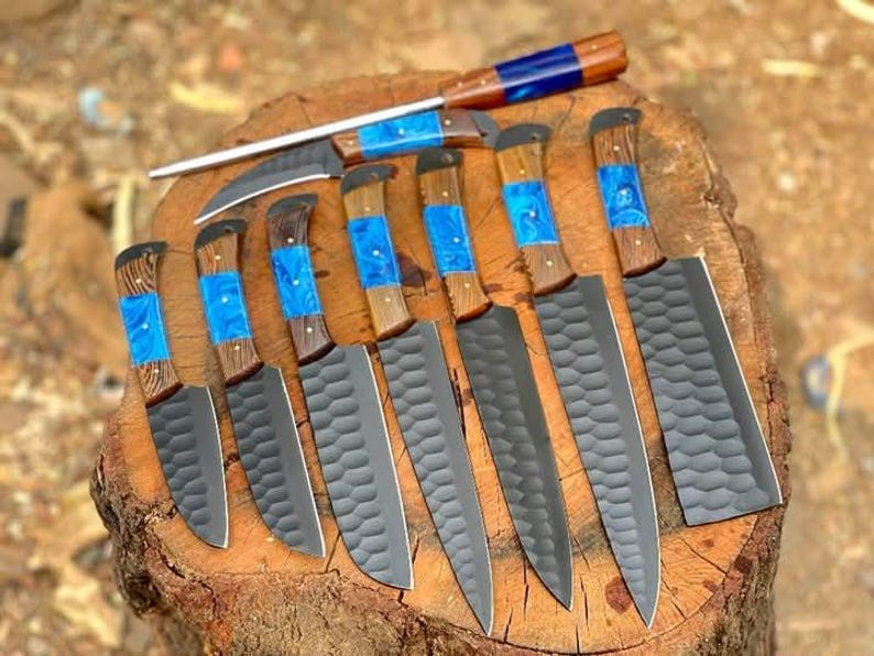 May include: A set of nine kitchen knives with black blades and wooden handles with blue resin inlays. The knives are arranged on a wooden surface.