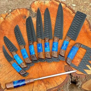 May include: A set of ten knives with black blades and blue and brown handles. The knives are arranged in a fan shape on a wooden surface.