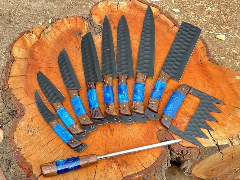 May include: A set of ten knives with black blades and blue and brown handles. The knives are arranged in a fan shape on a wooden surface.