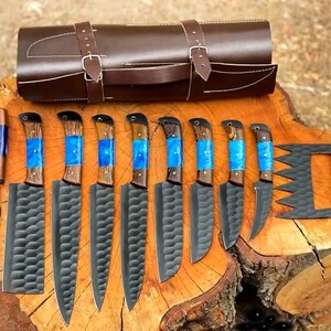 May include: A set of ten knives with blue and wood handles, a leather roll for storage, and a carving fork. The knives have black blades with a textured pattern.