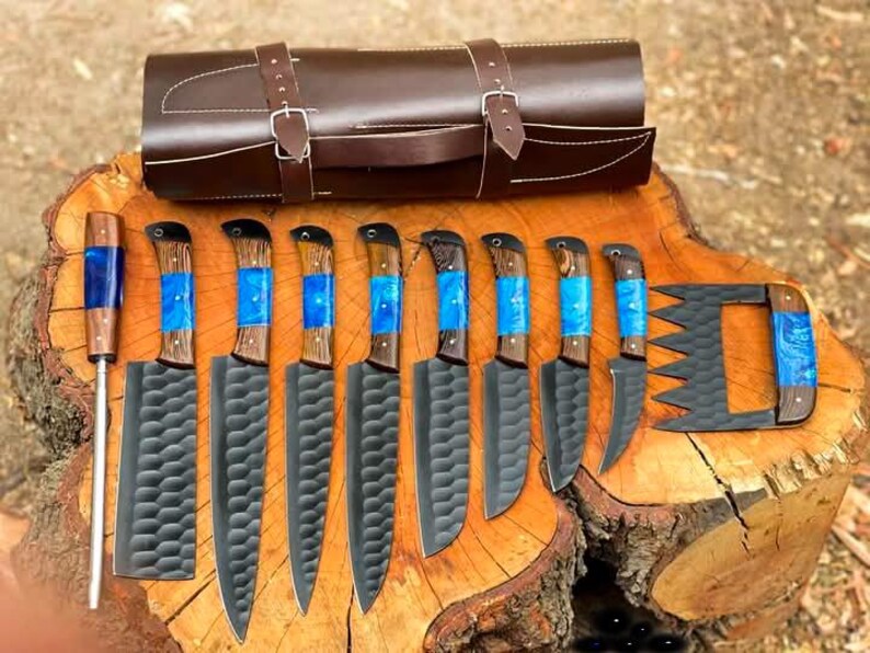 May include: A set of ten knives with blue and wood handles, a leather roll for storage, and a carving fork. The knives have black blades with a textured pattern.