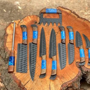 May include: A set of eight knives with blue and brown handles on a wooden surface. The knives have black blades with a textured pattern.